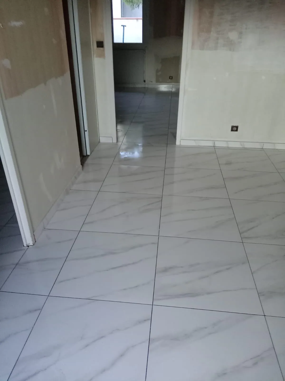 Sol en grands carreaux blancs veinés de gris qui court d’une pièce à l’autre, murs en reprise