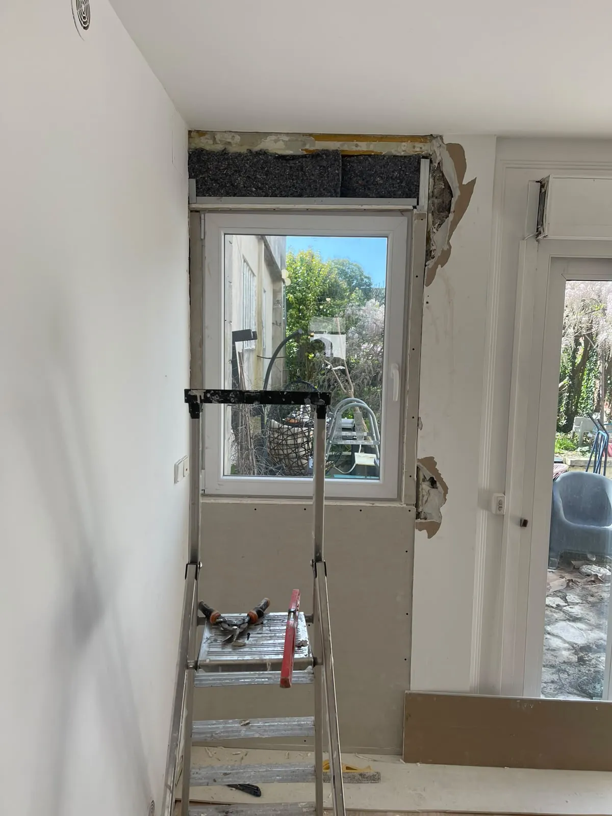 Fenêtre en cours de reprise : isolant posé au-dessus, plaques de plâtre au-dessous, escabeau devant