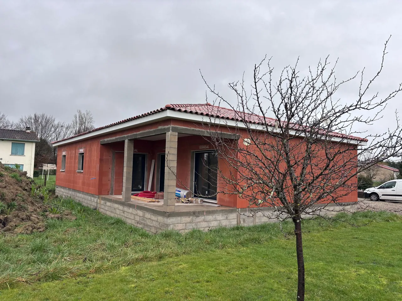 Maison neuve de plain-pied en briques de terre cuite, toiture en tuiles posée, terrasse couverte
