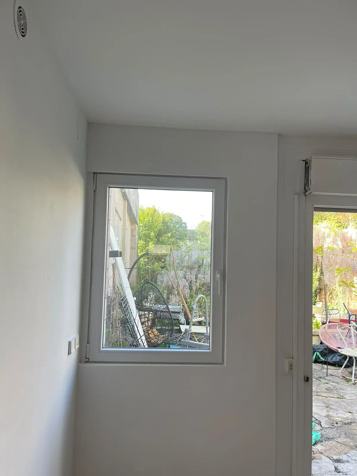 Pièce terminée : murs et plafond peints en blanc, fenêtre et porte-fenêtre ouvrant sur la cour