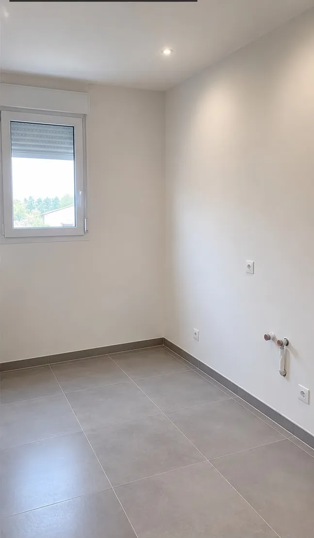 La même pièce refaite : murs lisses et peints, sol en grands carreaux gris, arrivées d’eau prêtes