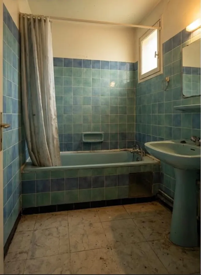 Salle de bains ancienne carrelée de bleu : baignoire, lavabo sur colonne, rideau de douche