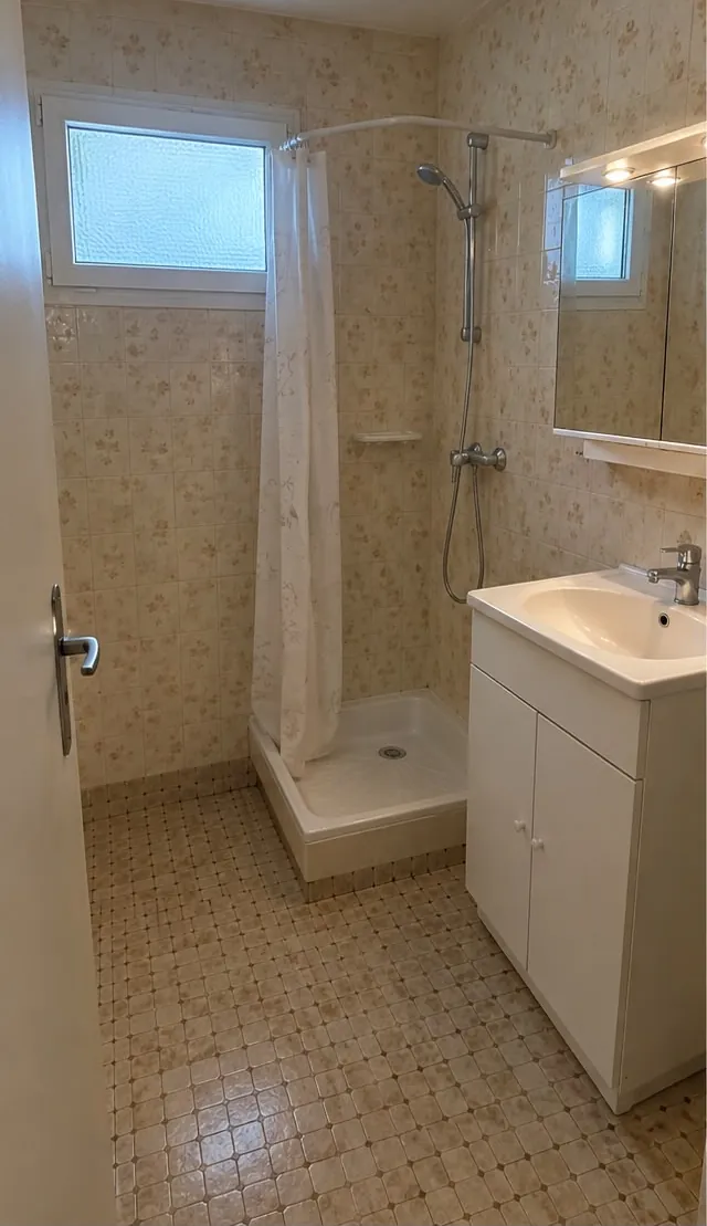 Salle d’eau ancienne : faïence beige, douche à rideau, meuble vasque blanc