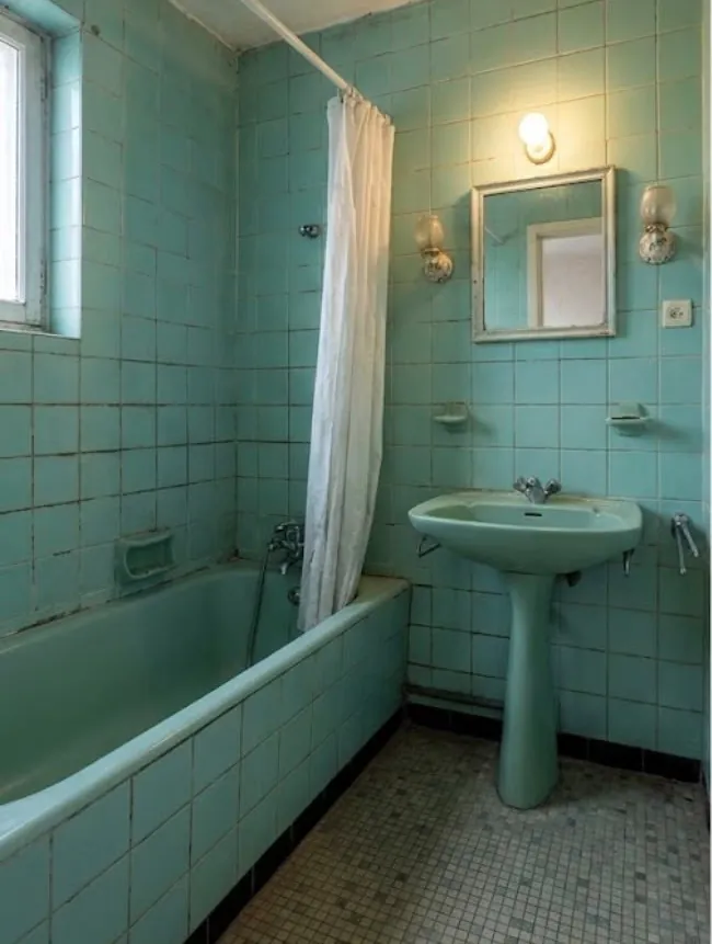 Salle de bains ancienne carrelée de vert : baignoire, lavabo sur colonne, rideau de douche