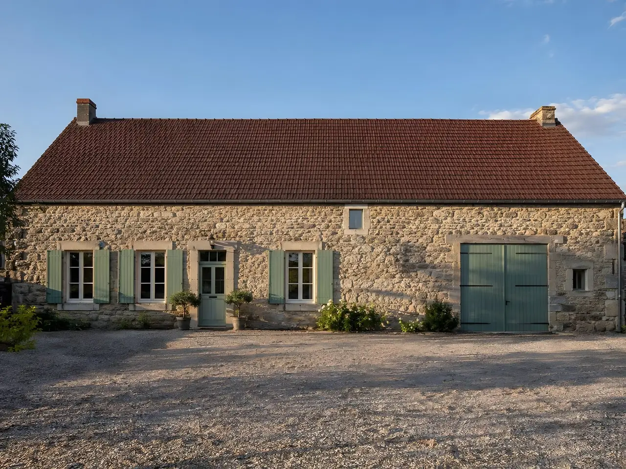 Longère en pierre aux volets vert pâle, long toit de tuiles brun-rouge bien plan, faîtage droit d’un pignon à l’autre