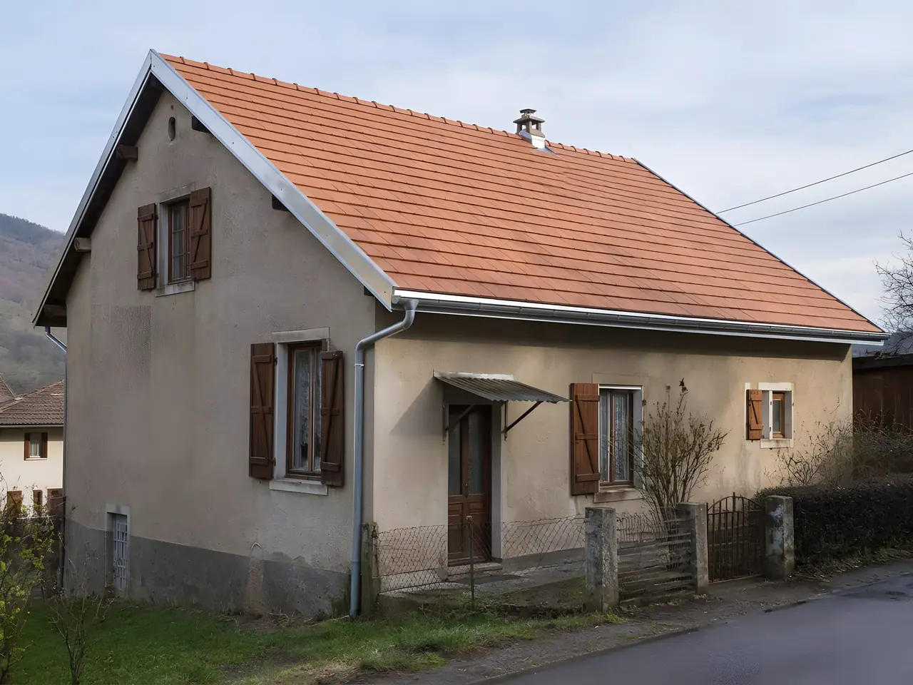 La même maison de village sous un toit neuf en tuiles orangées, faîtage droit, rives et gouttière neuves
