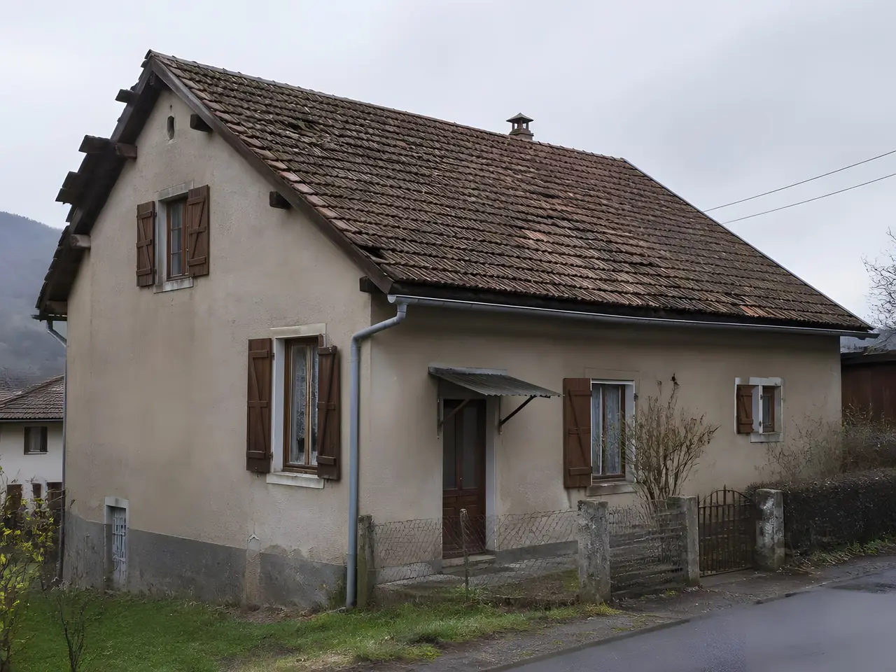Maison de village aux vieilles tuiles brunies, au toit bosselé et aux rives usées, avant sa réfection