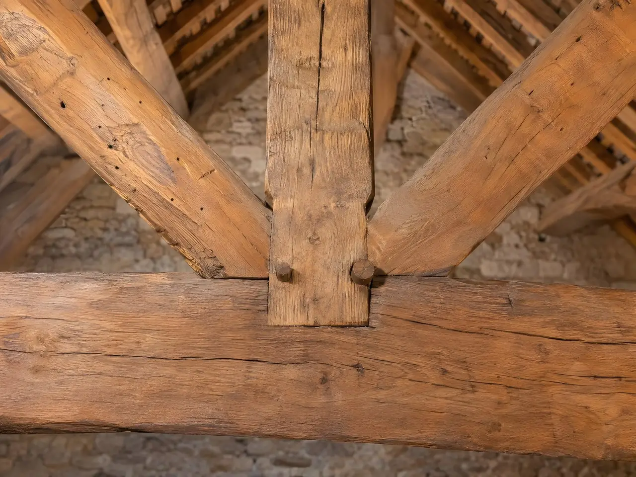 Assemblage de charpente en chêne brossé d’un brun miel, chevilles en bois et fentes du bois bien lisibles