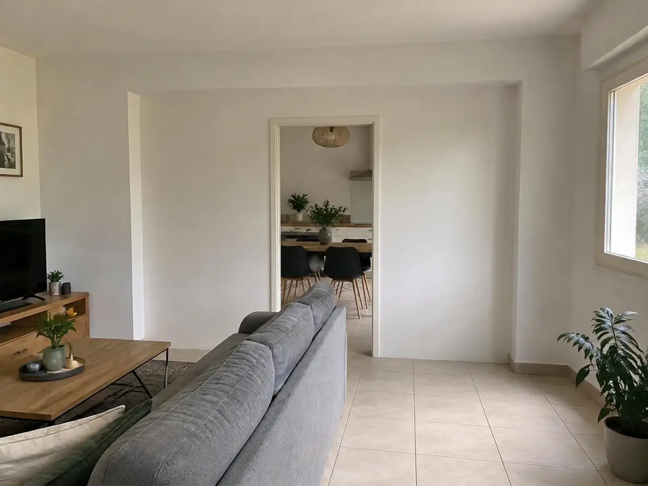 Mur blanc entre séjour et cuisine percé d’une simple porte, canapé gris devant, avant son ouverture