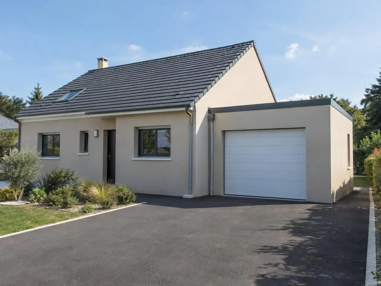 Pavillon crépi beige à toit de tuiles grises, garage accolé au pignon à toit plat, porte sectionnelle blanche