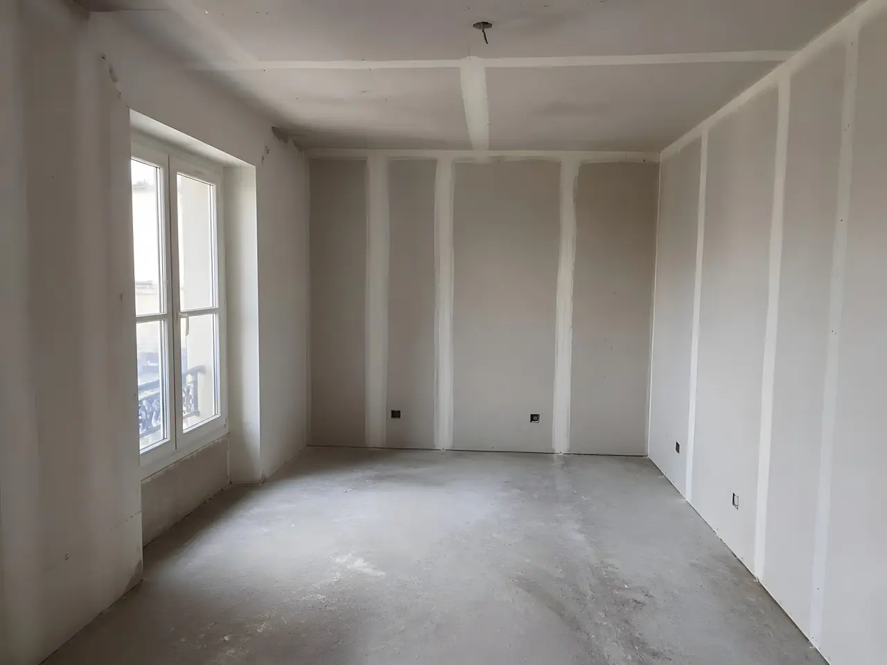 Pièce en placo neuf aux bandes de joints blanches bien visibles sur les murs et le plafond, avant peinture