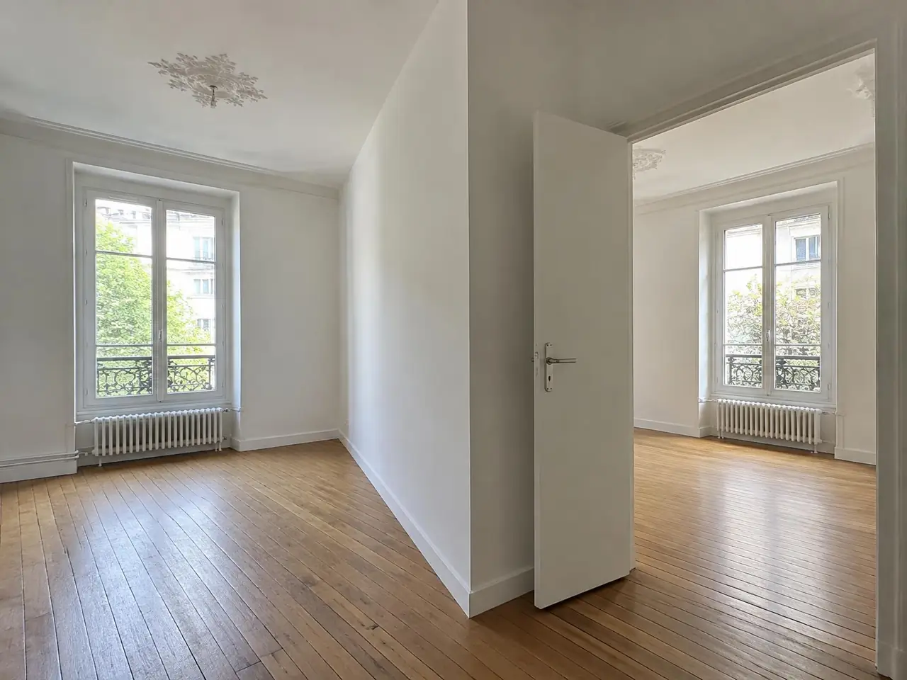 La même pièce coupée en deux par une cloison blanche, porte ouverte sur la seconde chambre