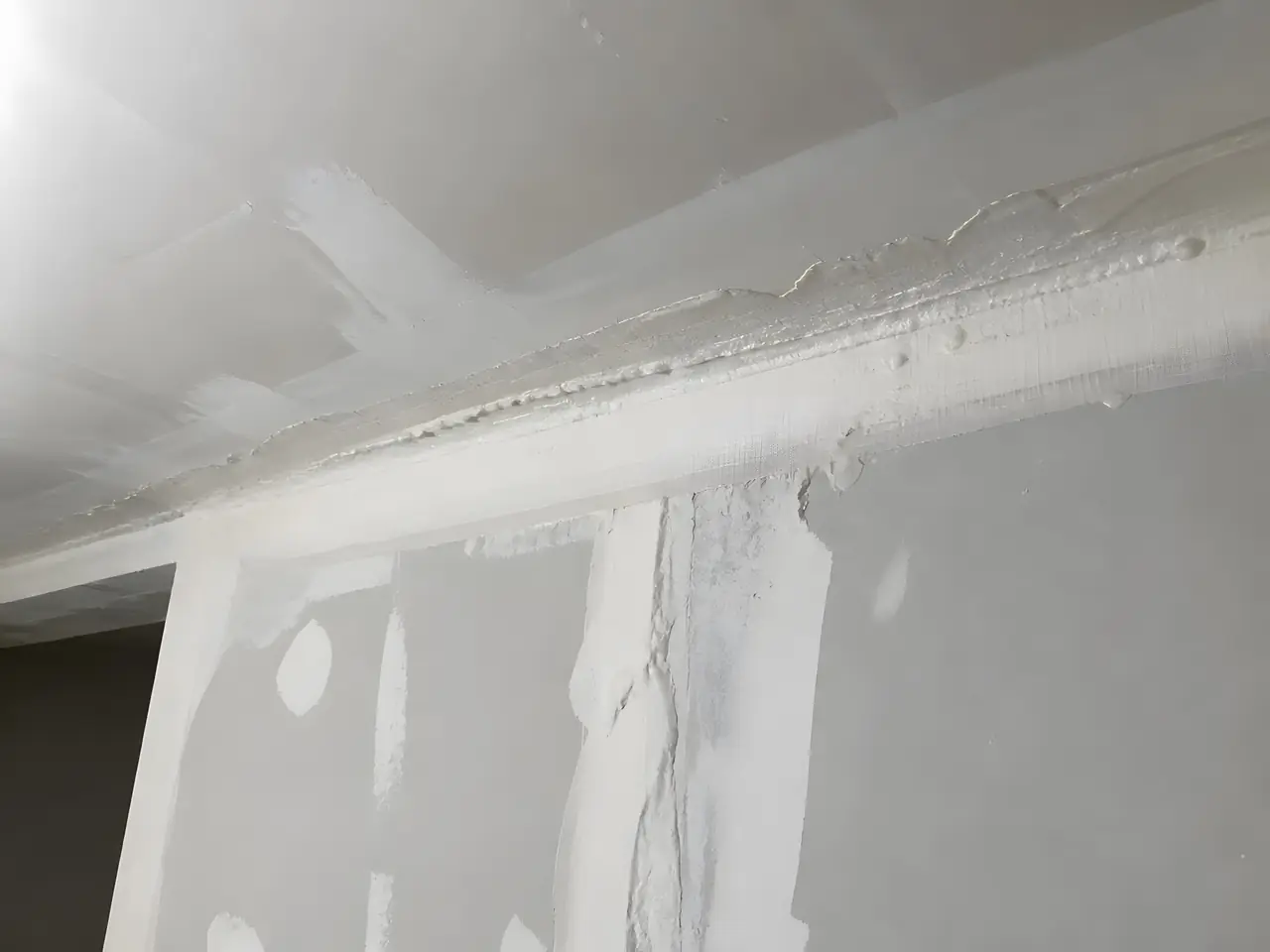 Angle de mur et de plafond en plaques, joints couverts d’une bande épaisse et d’enduit en paquets