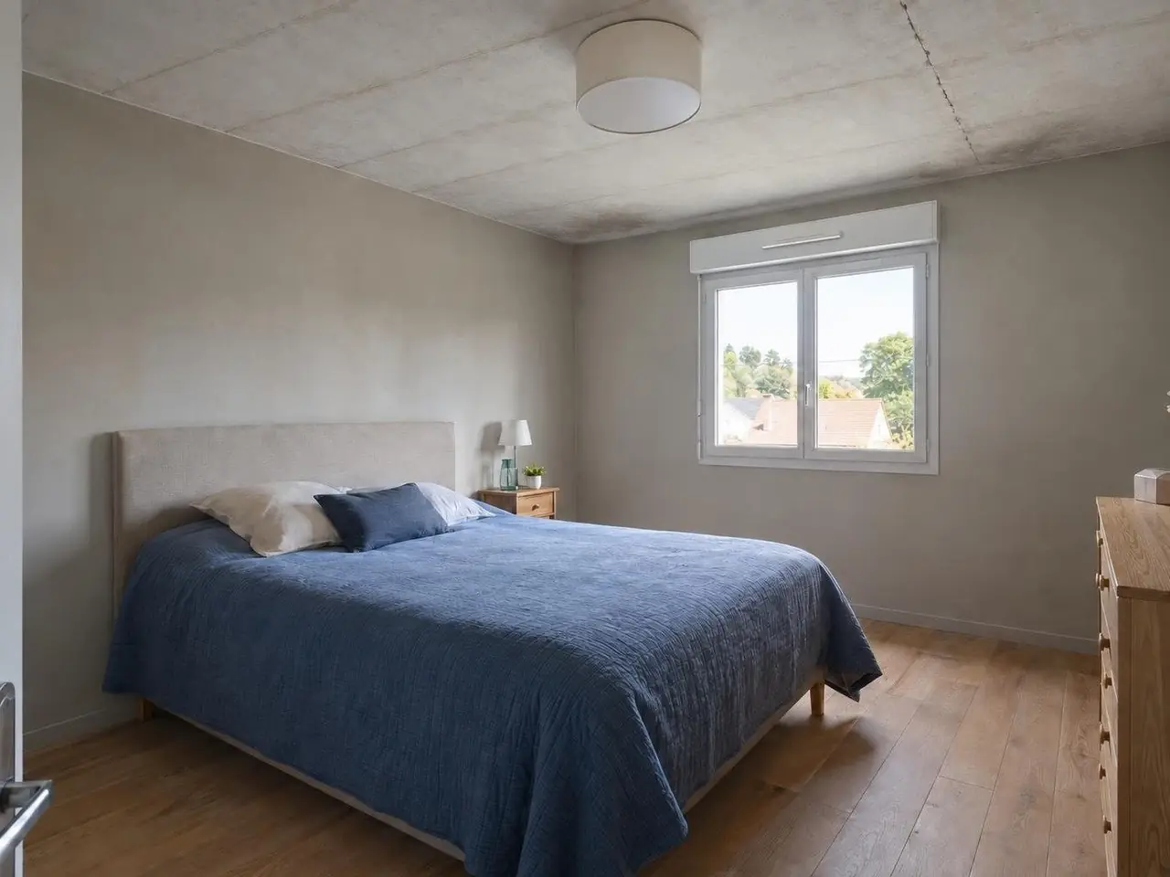 Chambre sous le grenier au plafond gris terne, marqué de lignes de joints régulières et d’une longue fissure