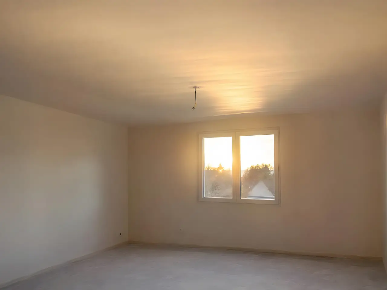 Chambre vide au plafond neuf lisse et uniforme, soleil couchant rasant par la fenêtre, fil du plafonnier au centre